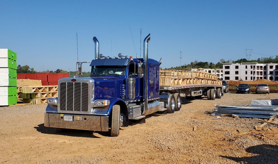 A roane transportation flatbed truck hauling something to a construction site